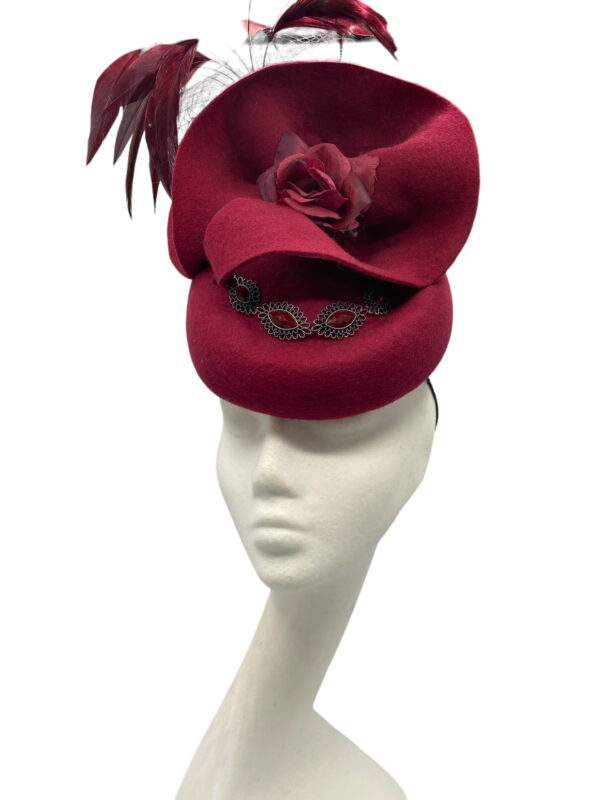 Burgundy/wine coloured pill box with veil and floaty feather detail.